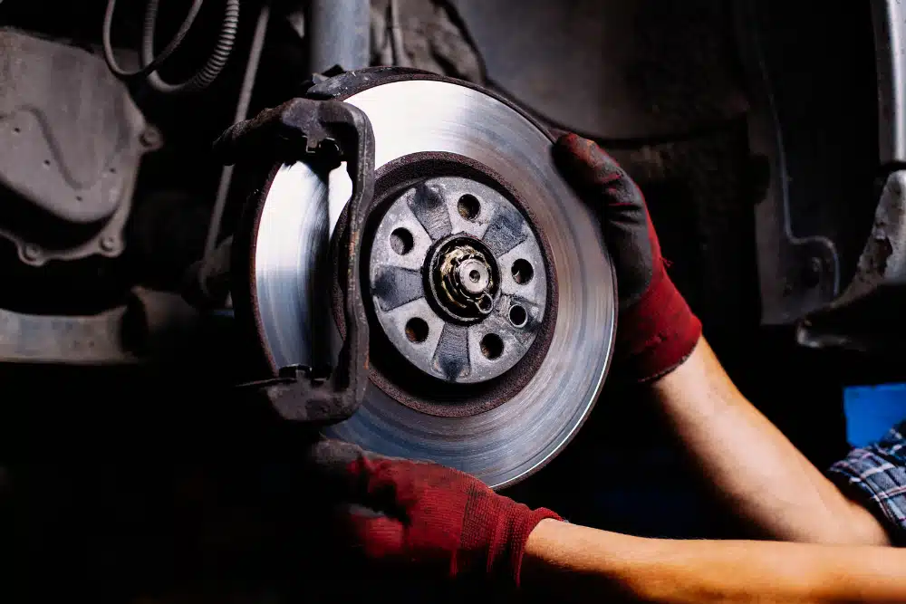 Mechanic replacing and inspecting a car brake disc during auto repair and maintenance service.