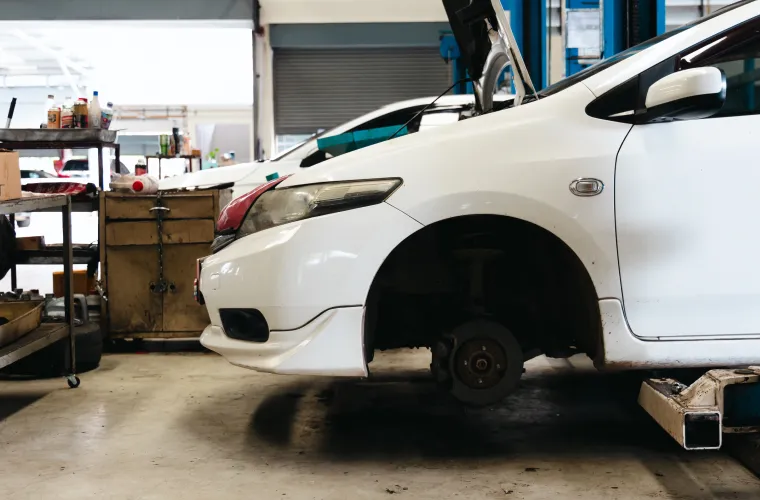 White Japanese car on lift, wheel removed at Pristine Motorsports in 950 S Dupont Blvd, Smyrna, DE.